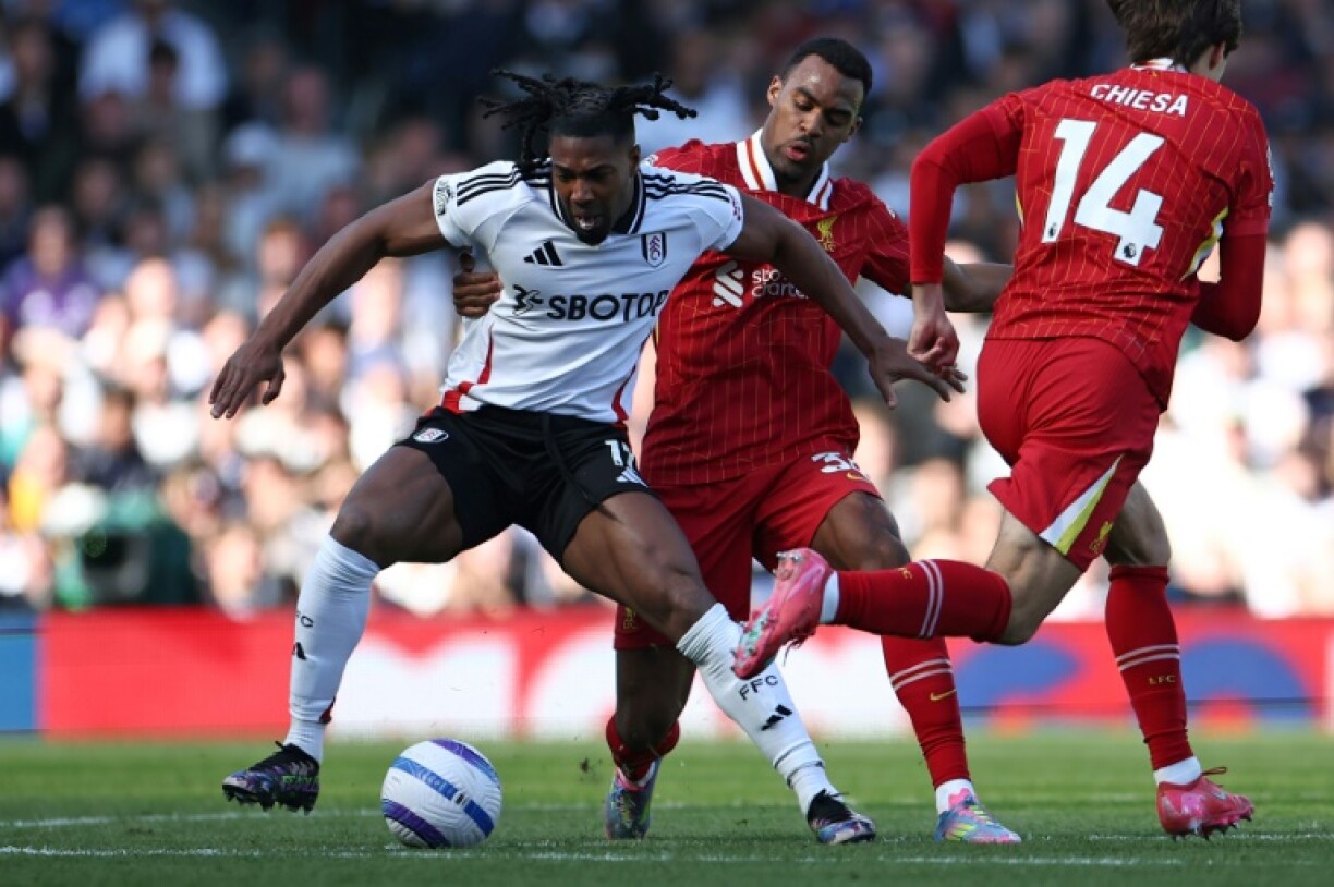Alex Iwobi (L) of Fulham shields the ball from Liverpool's Ryan Gravenberch (C)