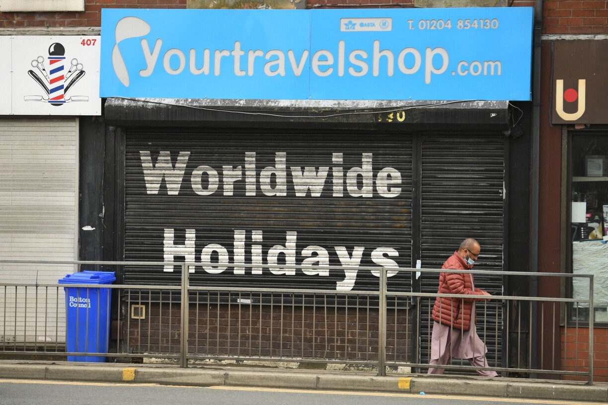 A pedestrian walks past a closed travel shop in Bolton, northwest England on May 14, 2021, as a Covid-19 variant of concern has been identified in the community.