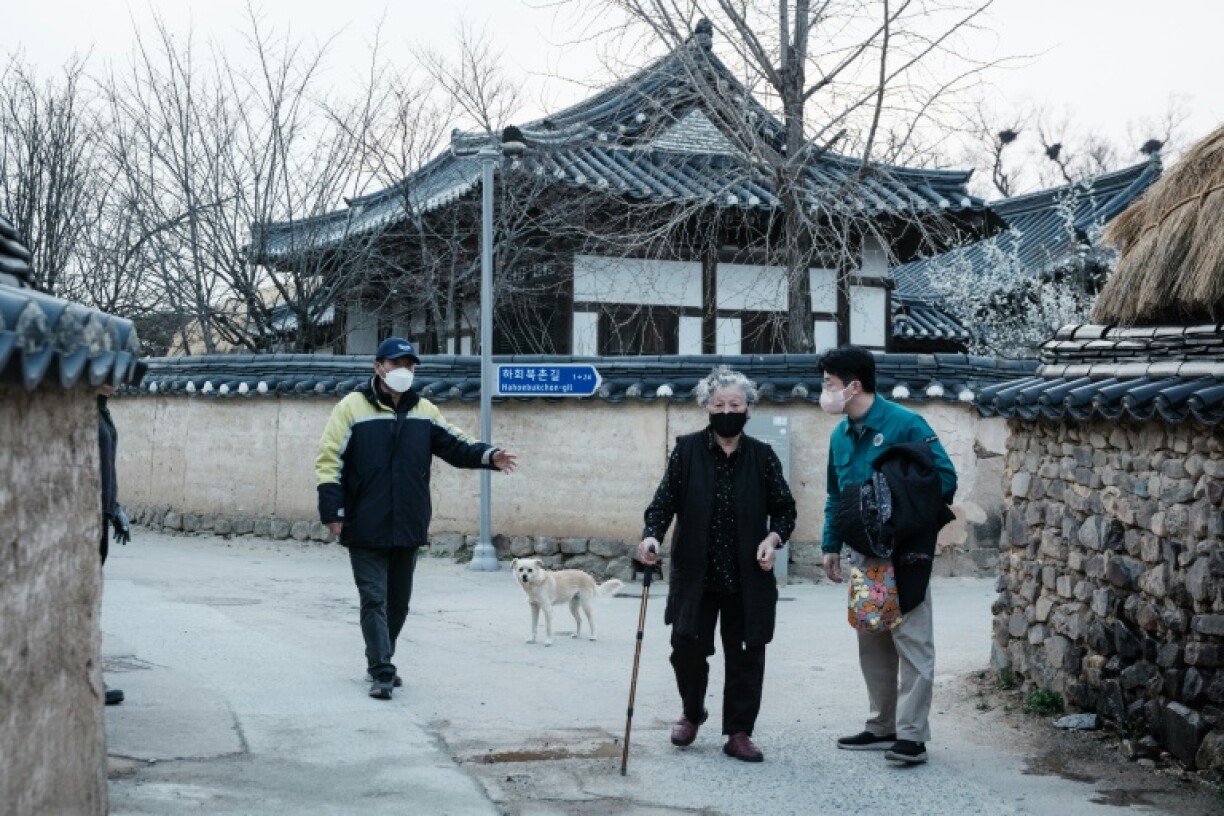 An old lady is escorted by a city official as she evacuates from her home in Andong Hahoe Folk Village