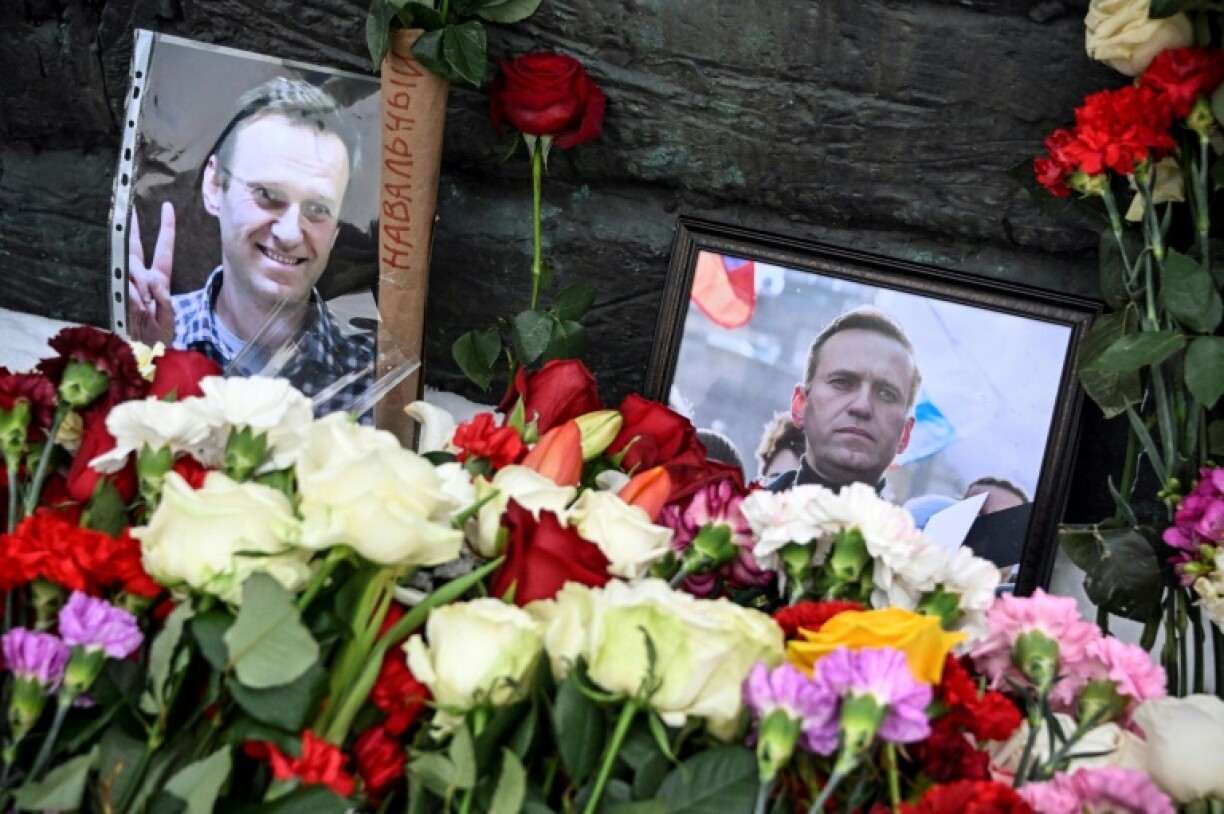 Des photos de l'opposant Alexeï Navalny sont exposées près de fleurs déposées au niveau du monument pour les victimes des répressions politiques, le 17 février 2024 à Moscou