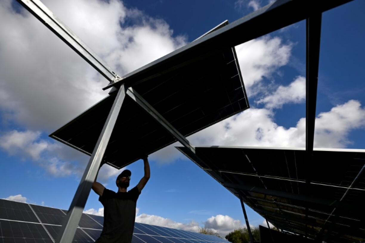 A worker installs a solar panel at a solar park near Erftstadt, western Germany on October 22, 2024