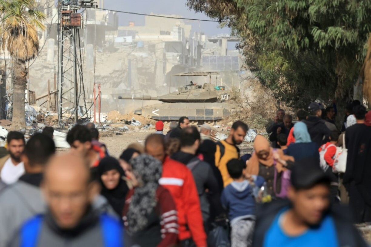 Un véhicule blindé israëlien passe devant des habitants fuyant les combats dans la bande de Gaza sur la route de Salaheddine dans le district de Zeitoun, dans le sud de la bande de Gaza, le 19 novembre 2023