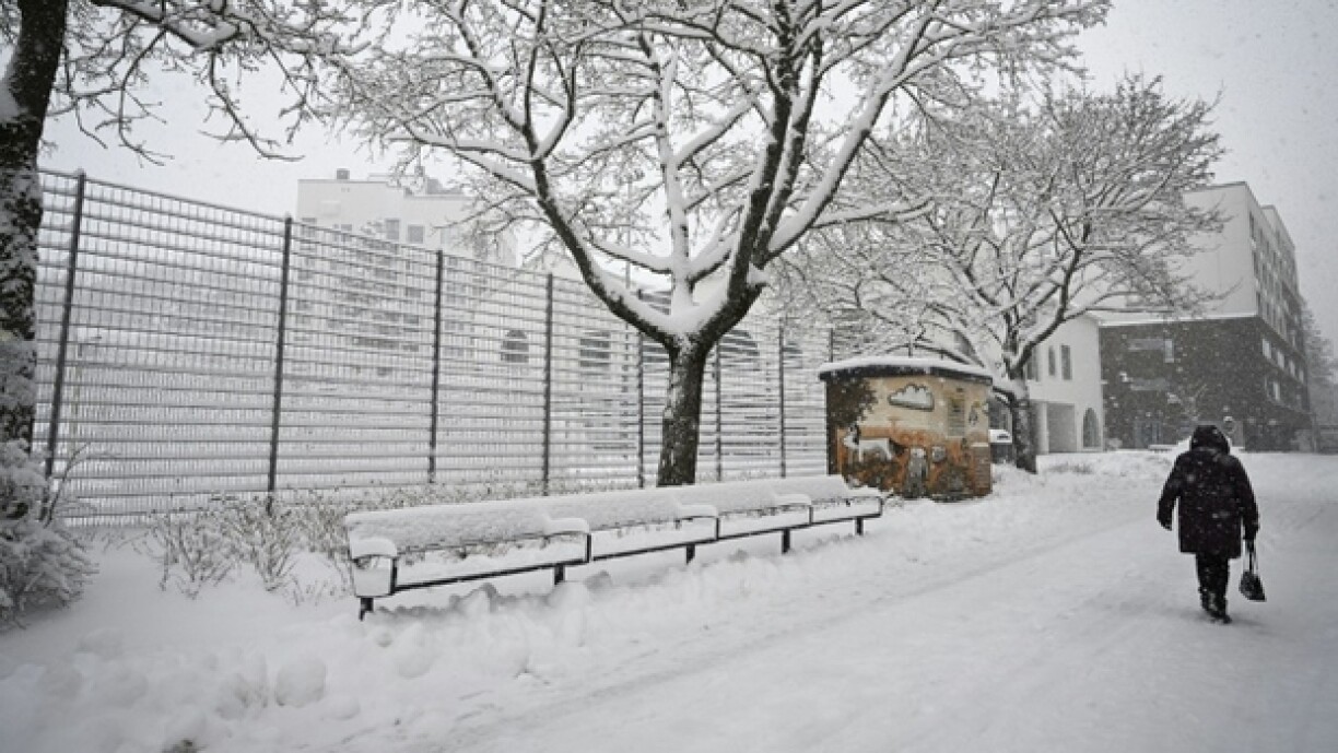 Un piéton marche dans une rue enneigée de Vantaa, en Finlande, le 23 avril 2024