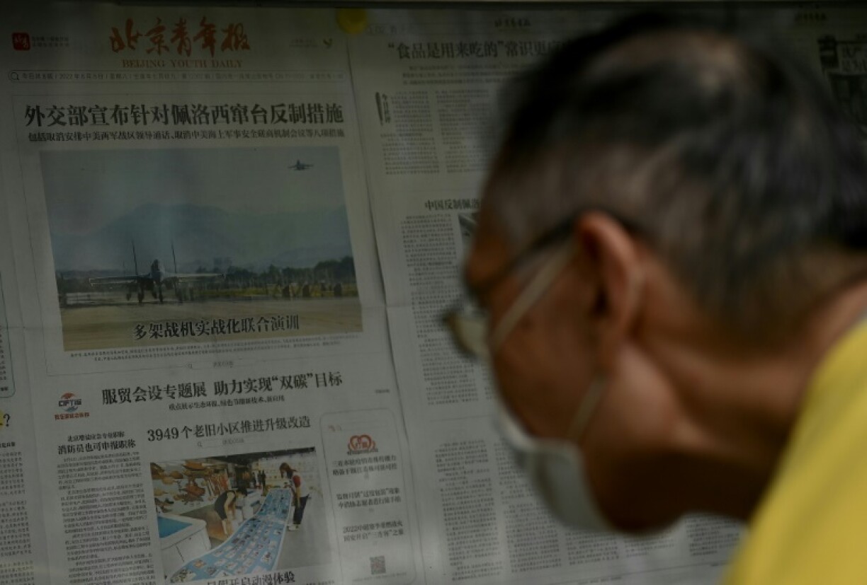 Homme lisant un journal rapportant les manoeuvres militaires chinoises à proximité de Taïwan, le 8 août 2022 à Pékin