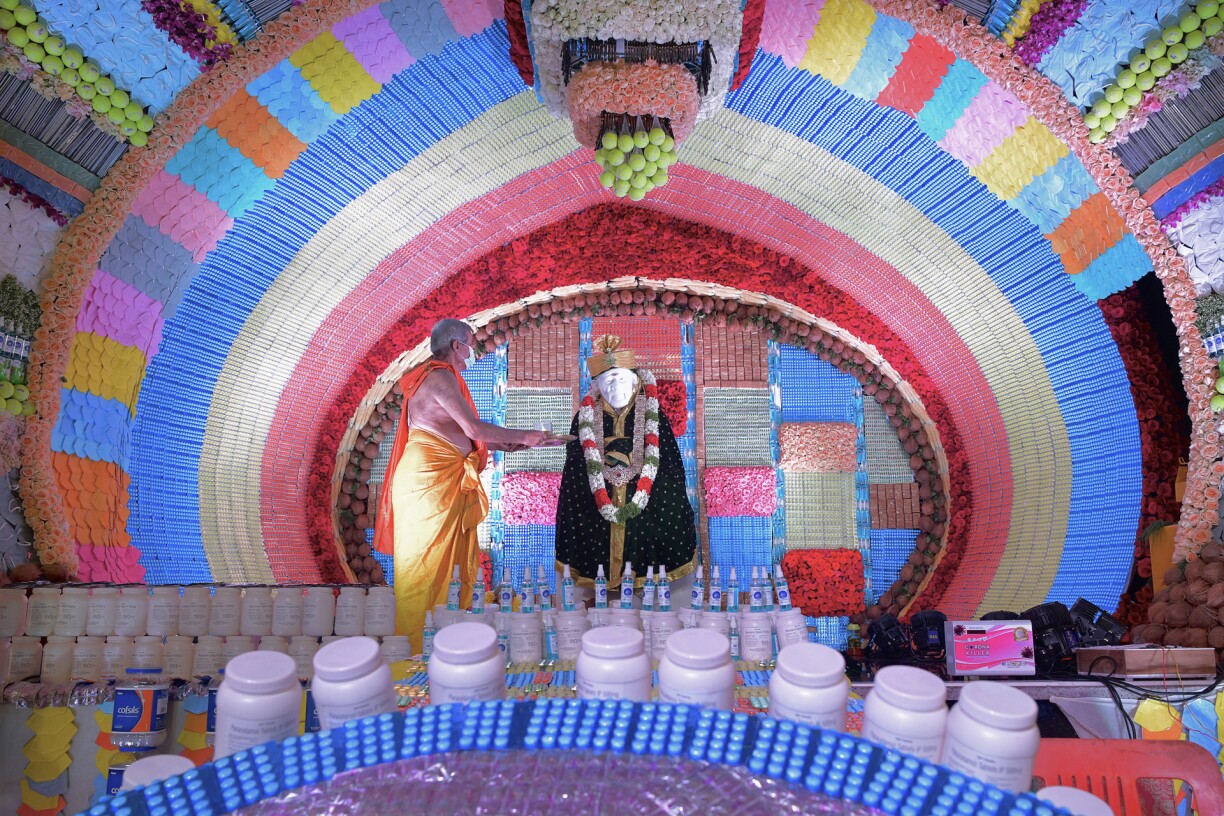 A Hindu priest makes an offering to an idol of Bhagwan Sai Baba inside Sai Baba Temple decorated with medicines, face masks and other items commonly used to prevent the Covid-19 coronavirus, during Guru Purnima celebrations in Bangalore on July 24, 2021.
