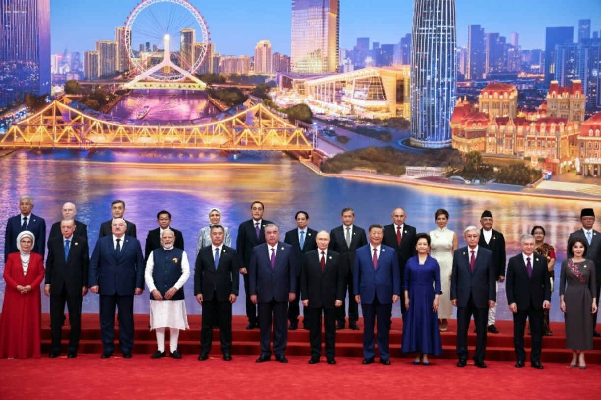 In this photograph distributed by the Russian state agency Sputnik, Russia's President Vladimir Putin, Chinese President Xi Jinping, his wife and foreign leaders pose during the Shanghai Cooperation Organization (SCO) Summit