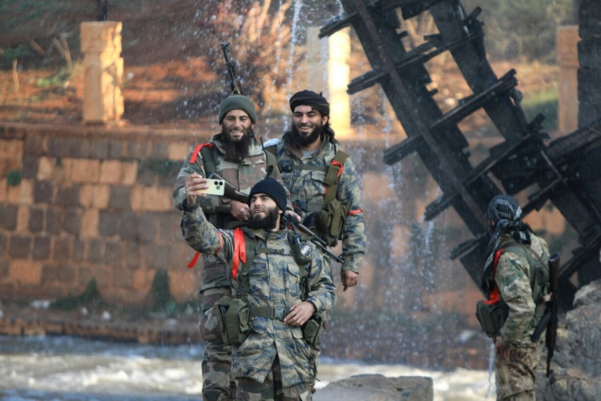 Rebel fighters take selfies alongside one of the landmark water wheels that dot the Orontes Valley around the central city of Hama
