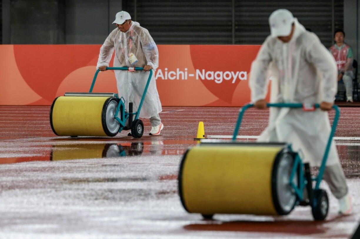 Officials dry the track as it rains on the athletics track on Monday