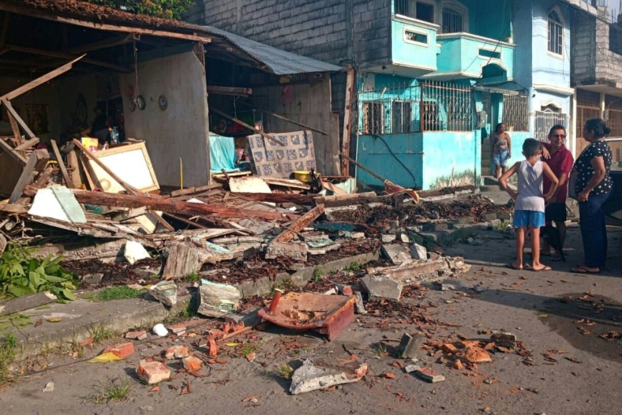 A family stands in front of a damaged house after the earthquake