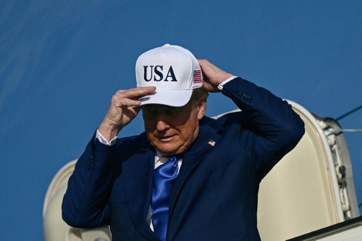 US President Donald Trump adjusts his cap as he exits Air Force One in Amsterdam