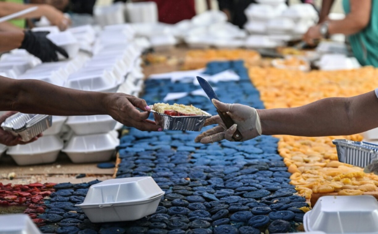 Des volontaires coupent des parts du gâteau géant aux couleurs du Venezuela pour les distribuer dans les abris où les victimes du tremblement de terre du 24 juin sont réfugiées, le 18 juillet à Caracas