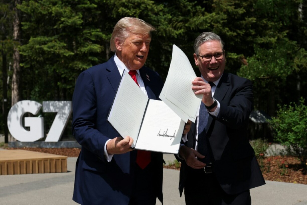 US President Donald Trump holds a signed US-UK trade deal next to British Prime Minister Keir Starmer