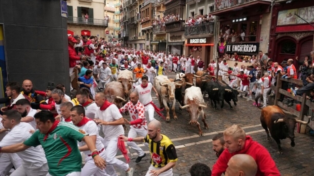 Des jeunes gens courent devant les taureaux lâchés dans les rues de Pampelune pour la fête de la San Fermin, le 7 juillet 2023 à Pampelune (nord de l'Espagne)