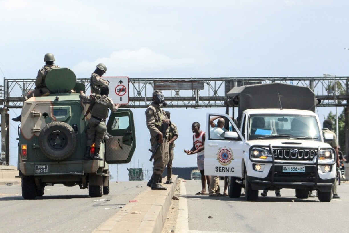 A man pleads with Mozambican policemen after they removed the body of a man killed during demonstrations that was left covered on a curb