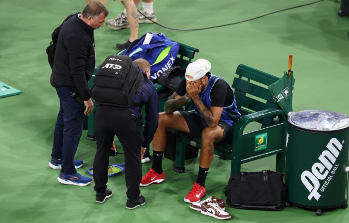 A devastated Nick Kyrgios is surrounded by trainers after retiring from his first-round match at Indian Wells because of wrist pain