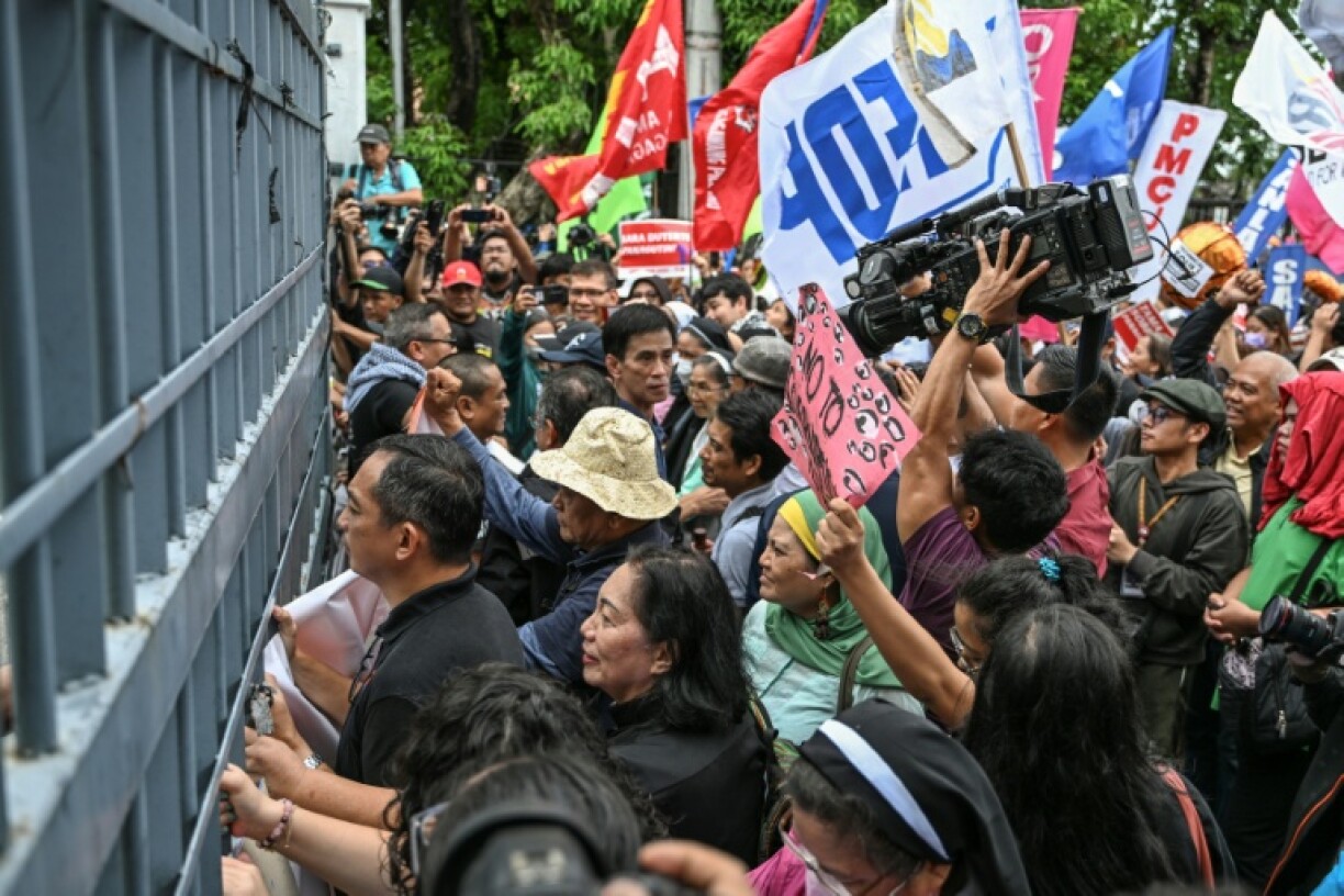 People bang on the gates of the Philippine Senate on Wednesday as they protest its decision to remand the impeachment case against Vice President Sara Duterte