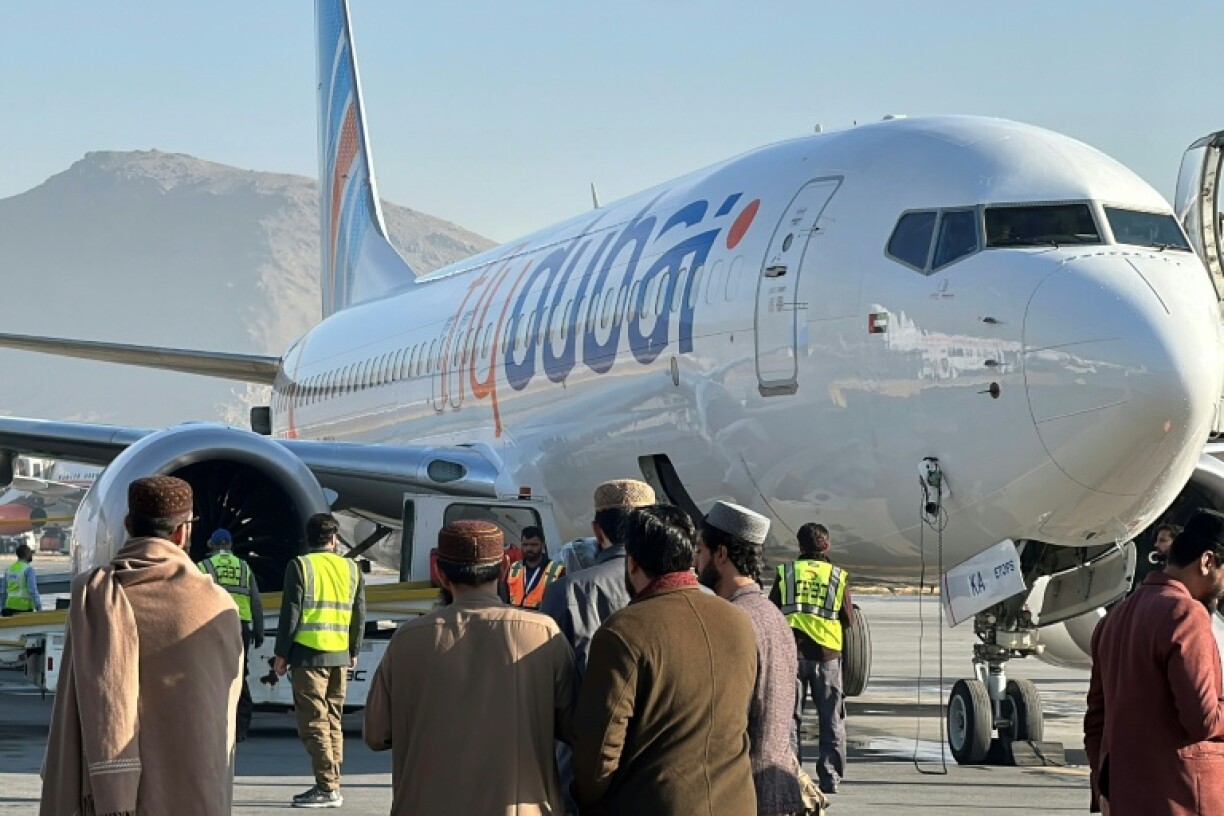 People stand on the tarmac next to a flydubai plane after it landed at Kabul airport in November 2023