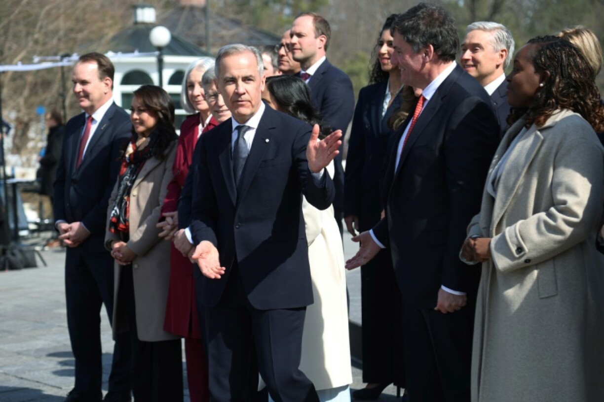 Canada's new Prime Minister Mark Carney (C) leads his cabinet after swearing-in to meet with reporters, before holding his first cabinet meeting