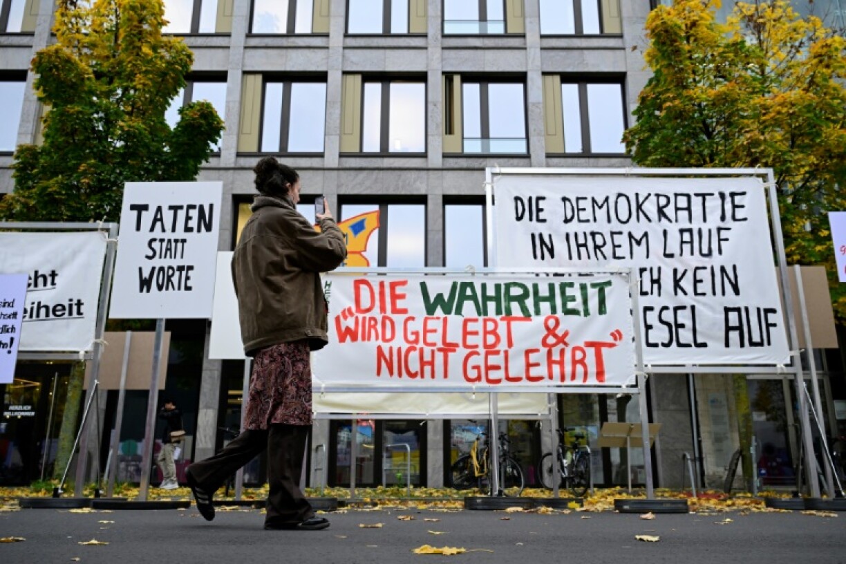 Une passante prend en photo des répliques de pancartes utilisées lors de manifestations en 1989, le 8 novembre 2024 à Berlin