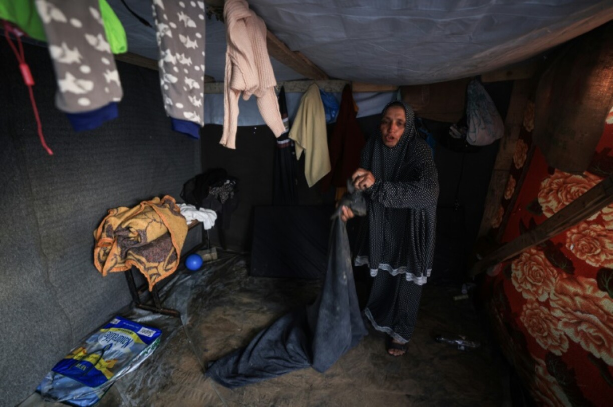Une femme trie des affaires mouillées par la pluie sous une tente à Rafah, dans le sud de la bande de Gaza, le 27 janvier 2024