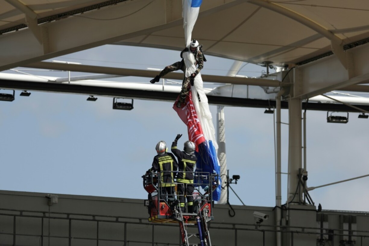 Firefighters work to unhook a parachutist from the roof of the stadium before kickoff in Toulouse