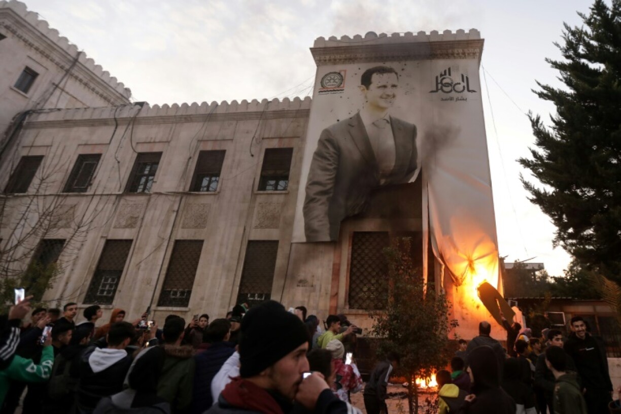 Hama residents set fire to a giant poster of Syrian President Bashar al-Assad on the facade of city hall after his forces abandoned the city