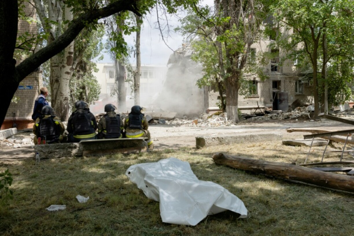 Des secouristes sont assis devant un corps sans vie avec un bâtiment effondré en arrière-plan après une frappe russe à Kramatorsk le 22 juin 2025