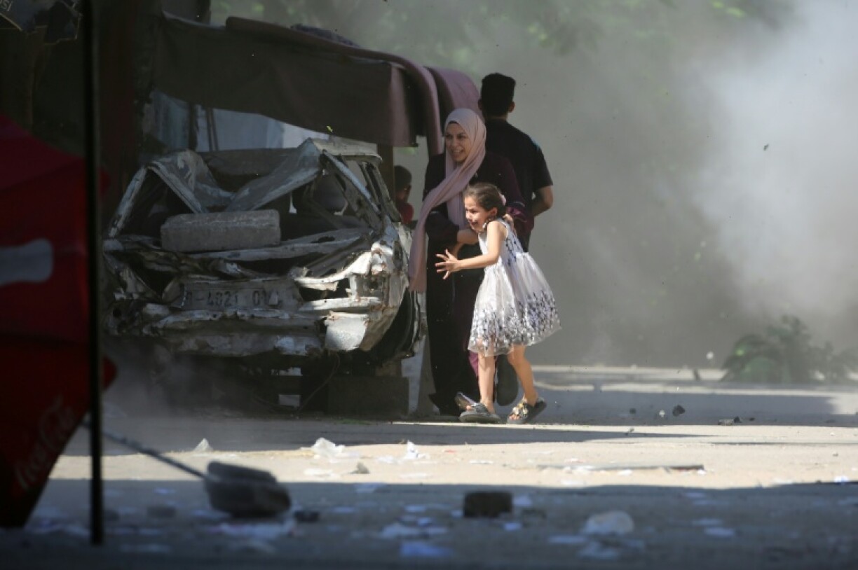 A Palestinian mother and her daughter rush for cover during an Israeli strike on Al-Bureij refugee camp in the central Gaza Strip.