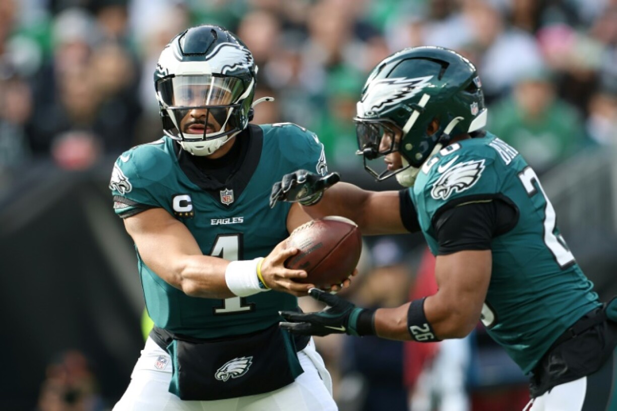 Philadelphia's Jalen Hurts, left, hands the ball to Saquon Barkley in the Eagles' NFL home victory over Carolina