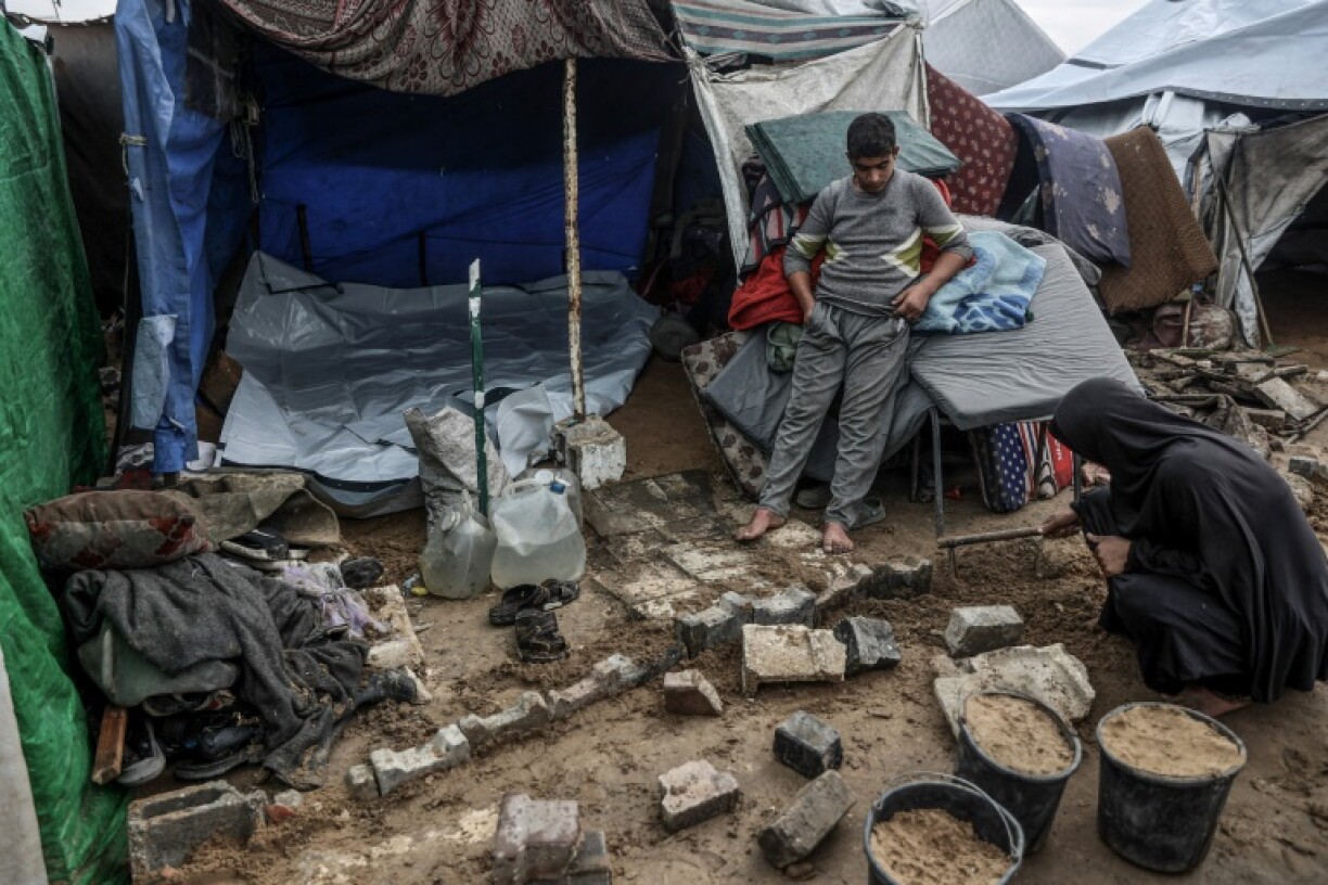 A Palestinian woman fixes her makeshift shelter at a displacement camp in Gaza City