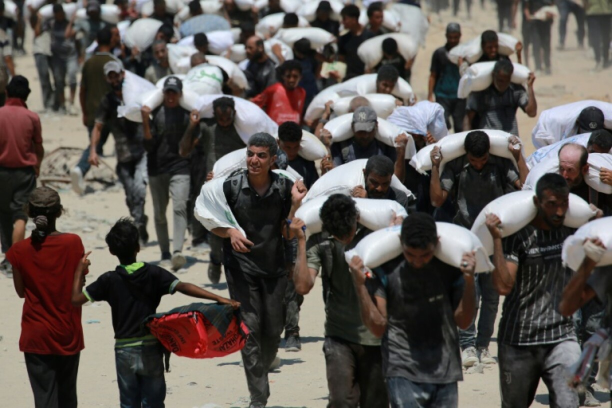 Palestinians carrying sacks of flour after trucks carrying humanitarian aid entered northern Gaza