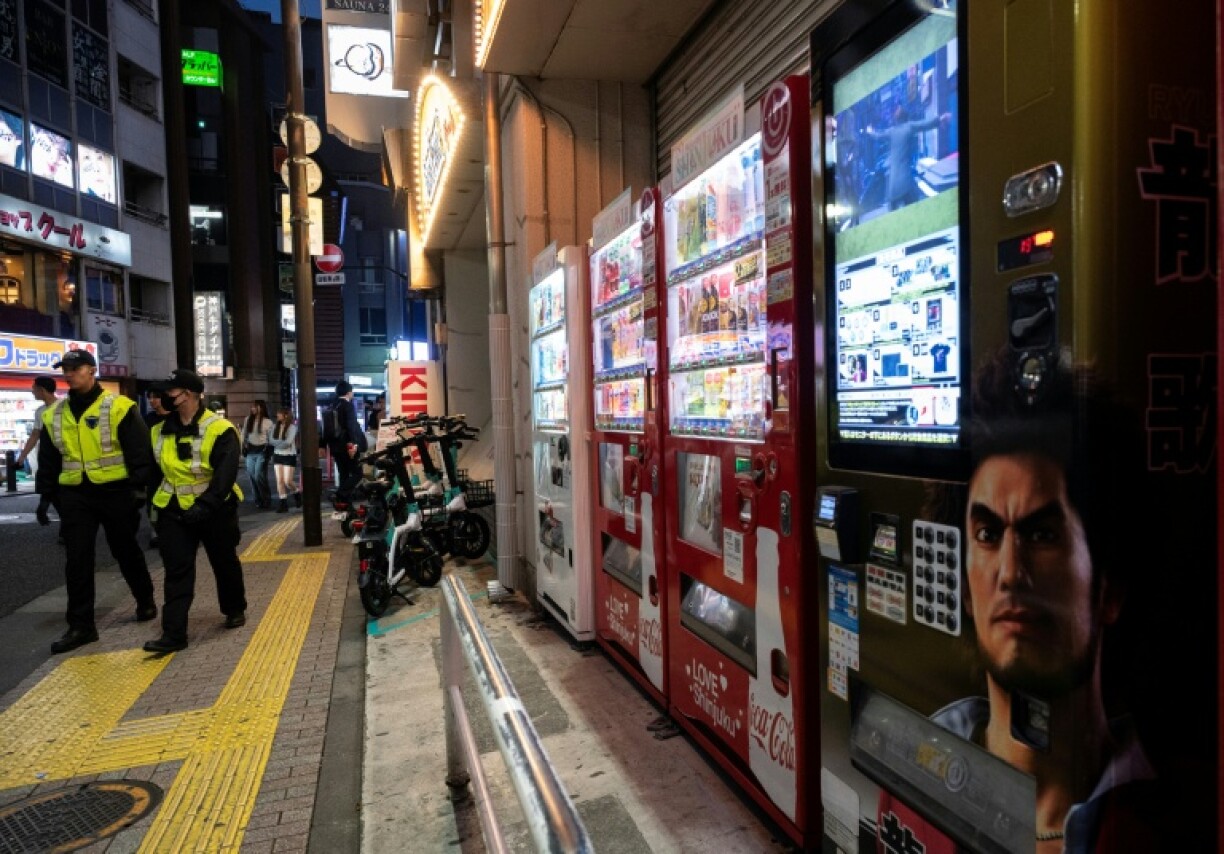 Des policiers passent près d'une rangée de distributeurs automatiques, le 13 avril 2026 à Tokyo