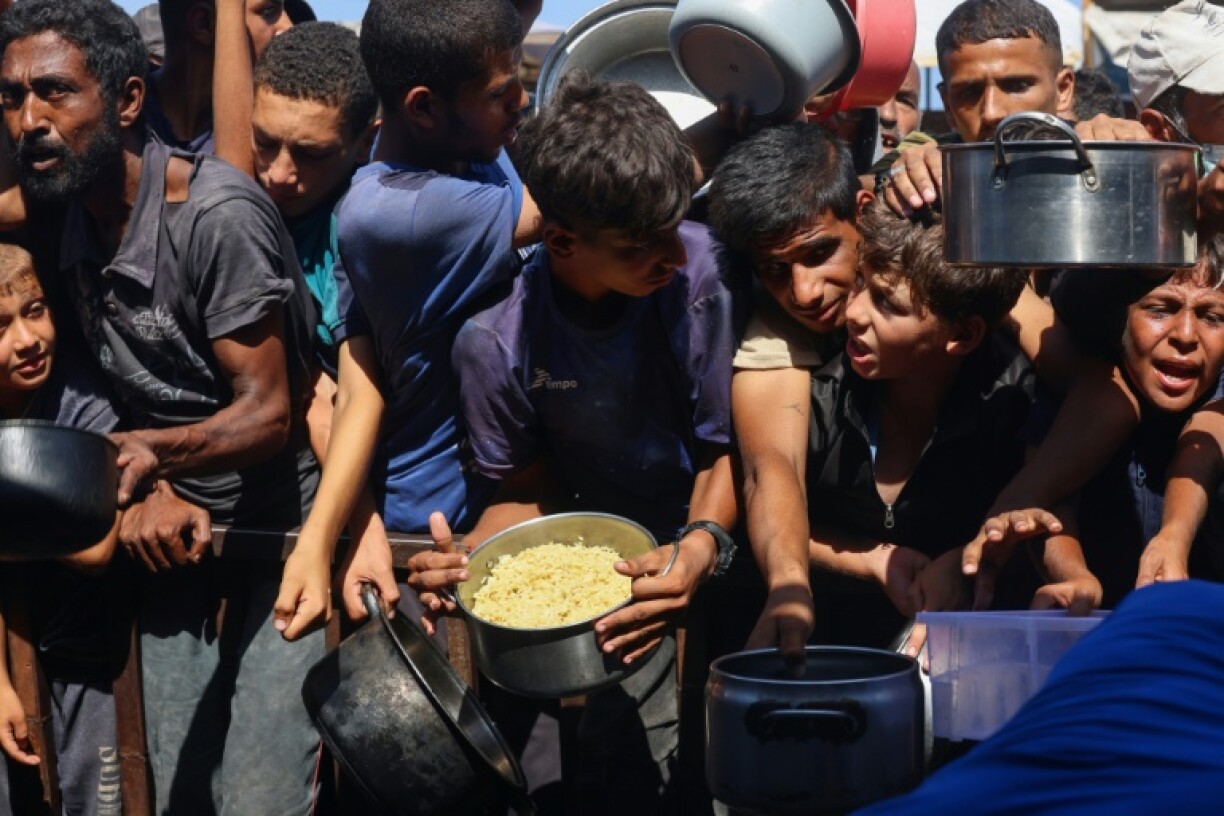 Palestinians receive food portions from a charity kitchen in the southern Gaza Strip, amid fears of famine spreading across the territory