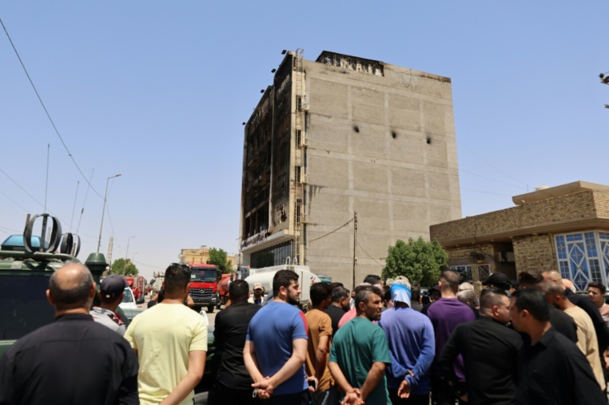 Onlookers gather in front of a shopping mall in the eastern Iraqi city of Kut after a fire tore through it, killing at least 60 people