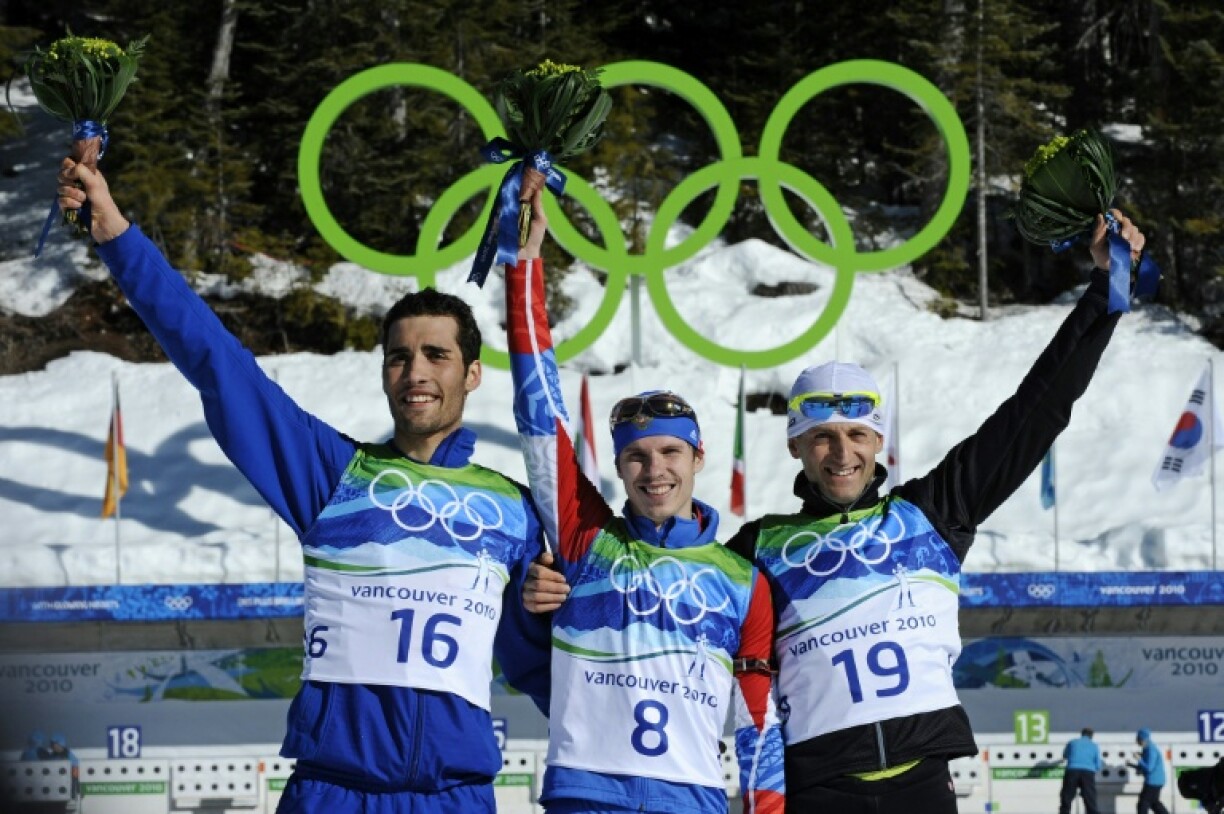 Le médaillé d'or russe Evgeny Ustyugov (au centre), le médaillé d'argent français Martin Fourcade (à gauche) et le médaillé de bronze slovaque Pavol Hurajt sur le podium après le 15 km mass start du biathlon au parc olympique de Whistler pendant les Jeux olympiques d'hiver de Vancouver, le 21 février 2010