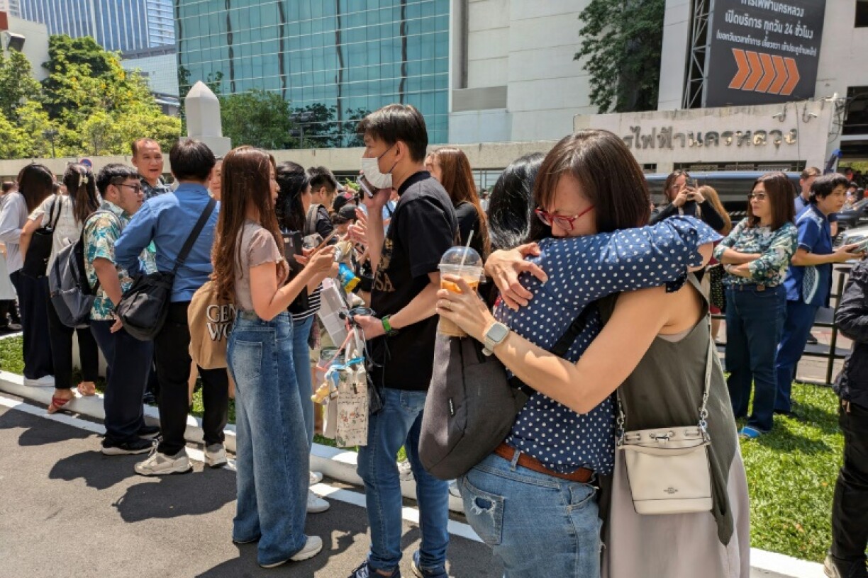 Office workers embraced after fleeing their buildings because of the earthquake