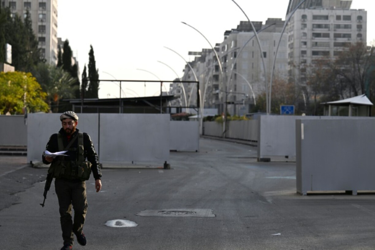 A Syrian rebel fighter stands guard outside the long-feared defence ministry compound in central Damascus from which the Assads' myriad intelligence agencies operated.