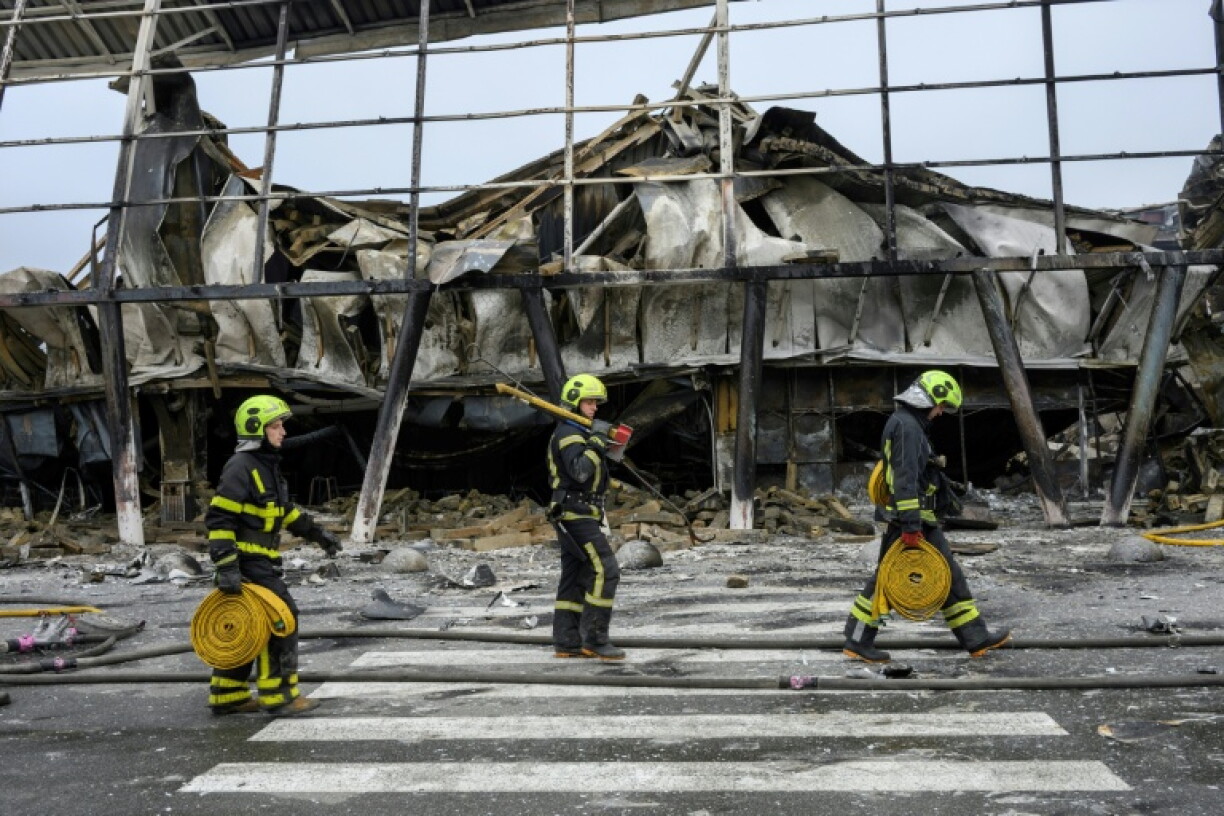 Ukrainian rescuers walk at the site of a shopping centre damaged following a missile strike in Kyiv