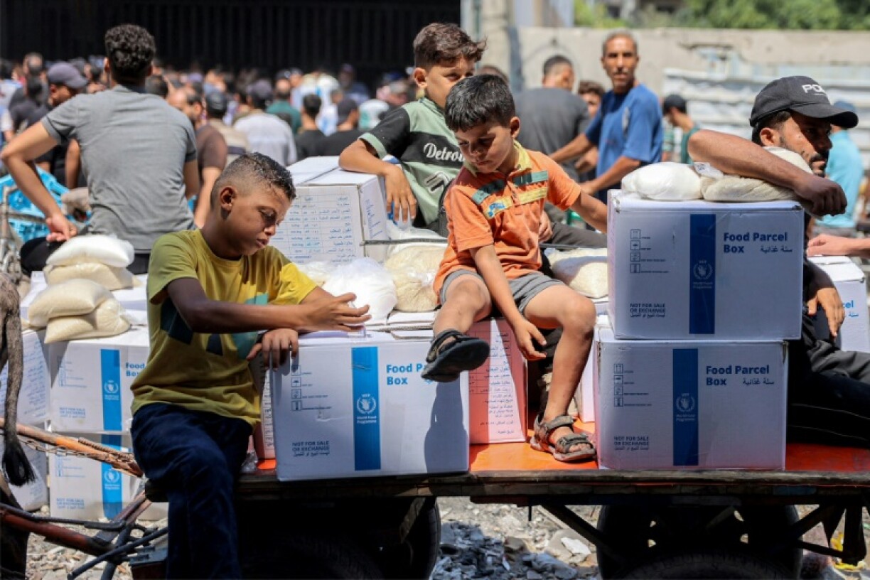 Des garçons sont assis près de paquets d'aide humanitaire fournis par l'agence de l'ONU pour les réfugiés palestiniens (Unrwa) dans le centre de la ville de Gaza le 27 août 2024