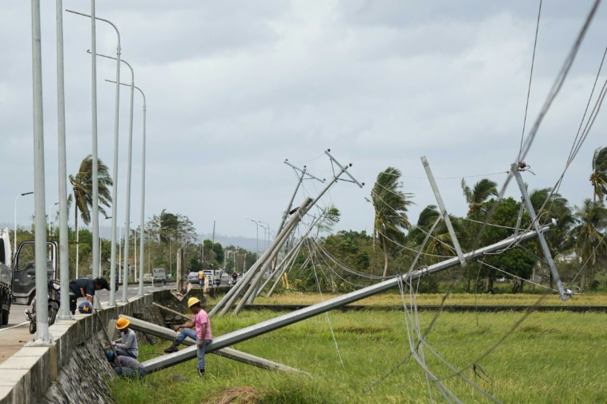 Workers tend to electric posts toppled by strong wings brought about by Typhoon Fung-wong in Albay province