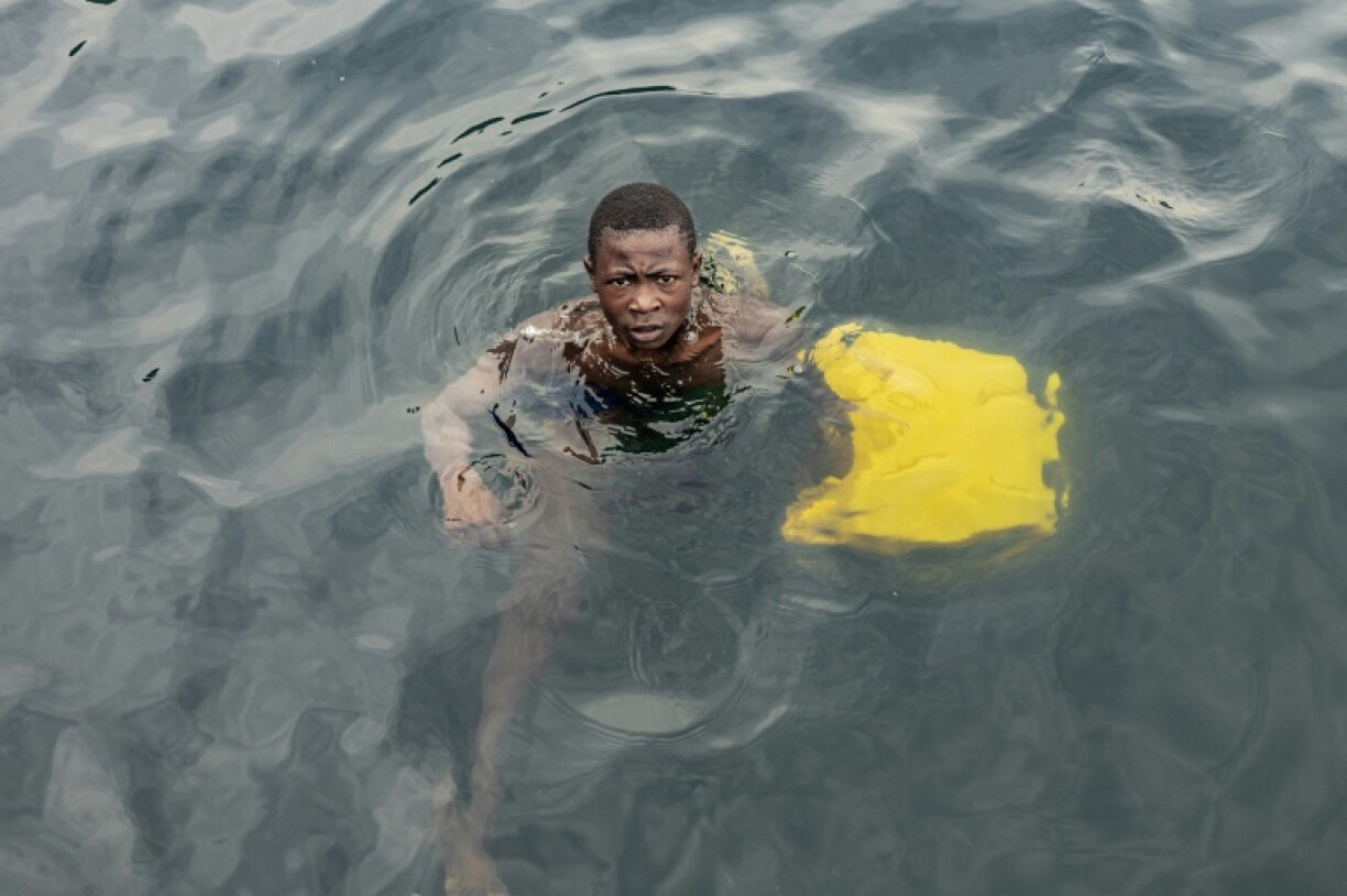 A boy swims with a jerrycan to collect water from Lake Kivu