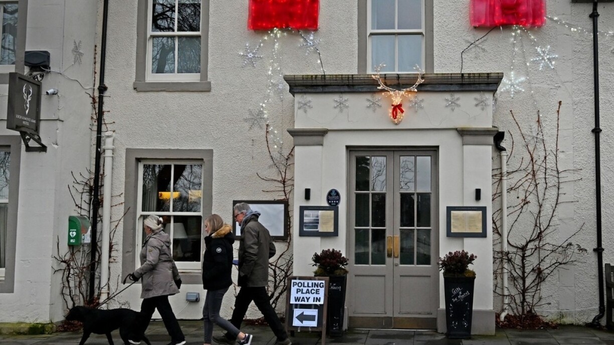 A family arrive with a dog at a polling station, set up inside The Loch Lomond Arms, in Luss, Scotland as Britain holds a general election on December 12, 2019.