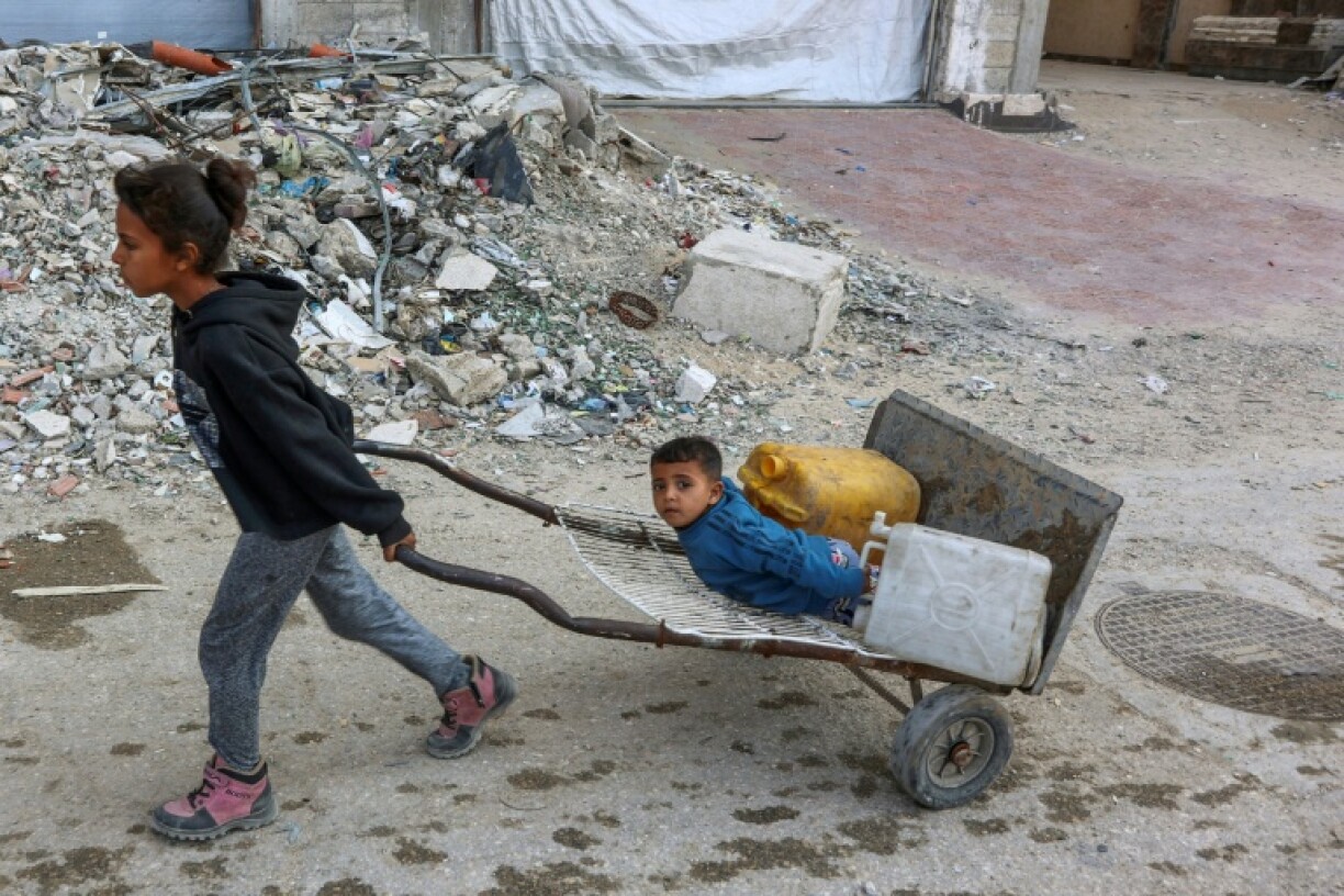 Palestinian children head to a water distribution point to fill their containers in Gaza City
