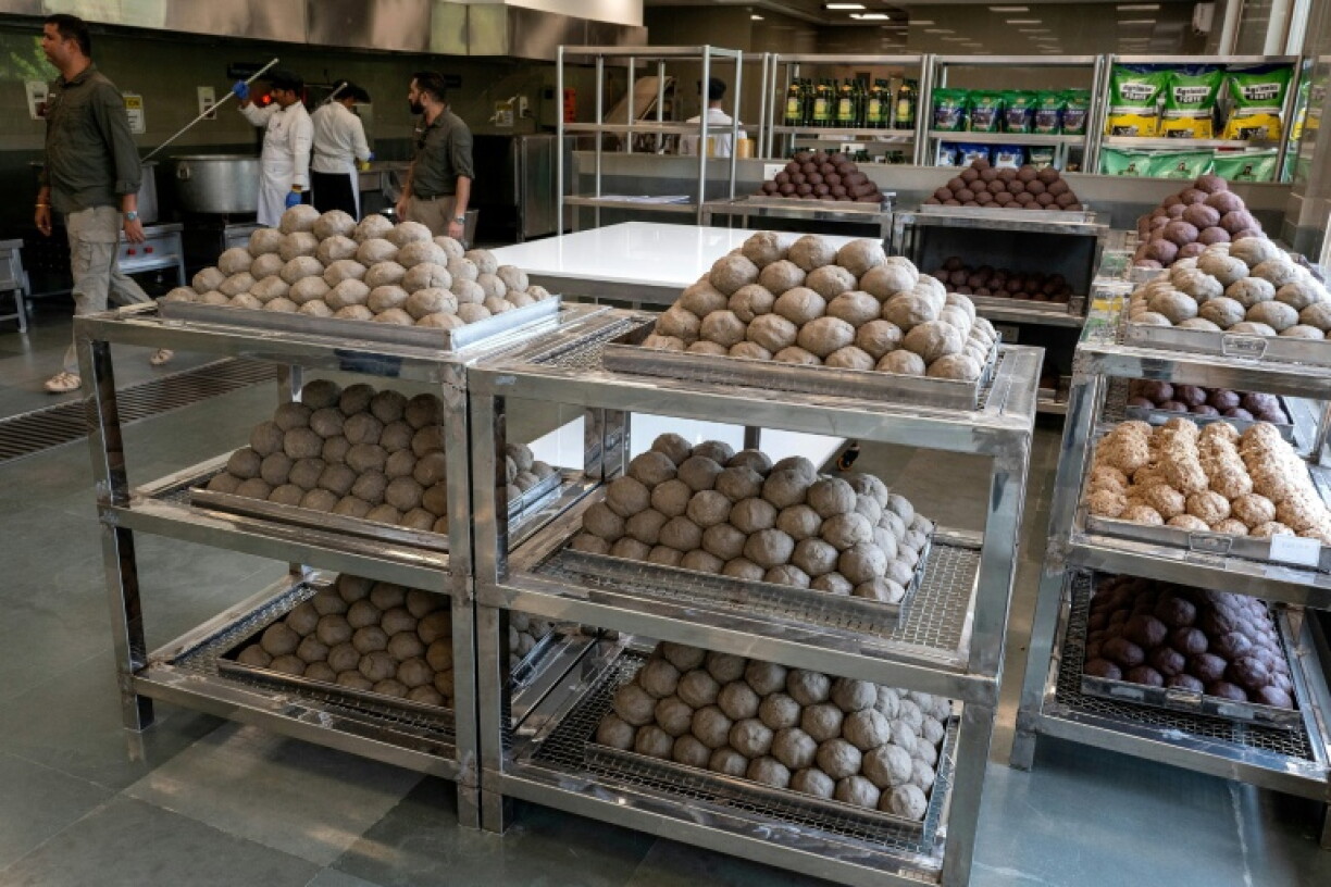 Cooks preparing meals beside trays of elephant food in a kitchen at Vantara
