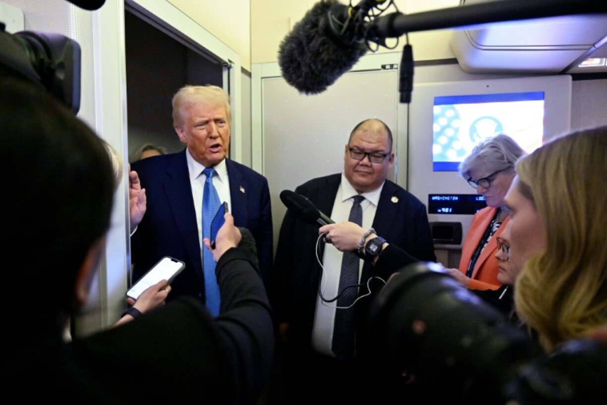 Le président américain Donald Trump s'entretient avec des journalistes, aux côtés du directeur de la communication de la Maison Blanche, Steven Cheung (c), à bord d'Air Force One, en route de Miami, en Floride, à la Maison Blanche, le 19 février 2025