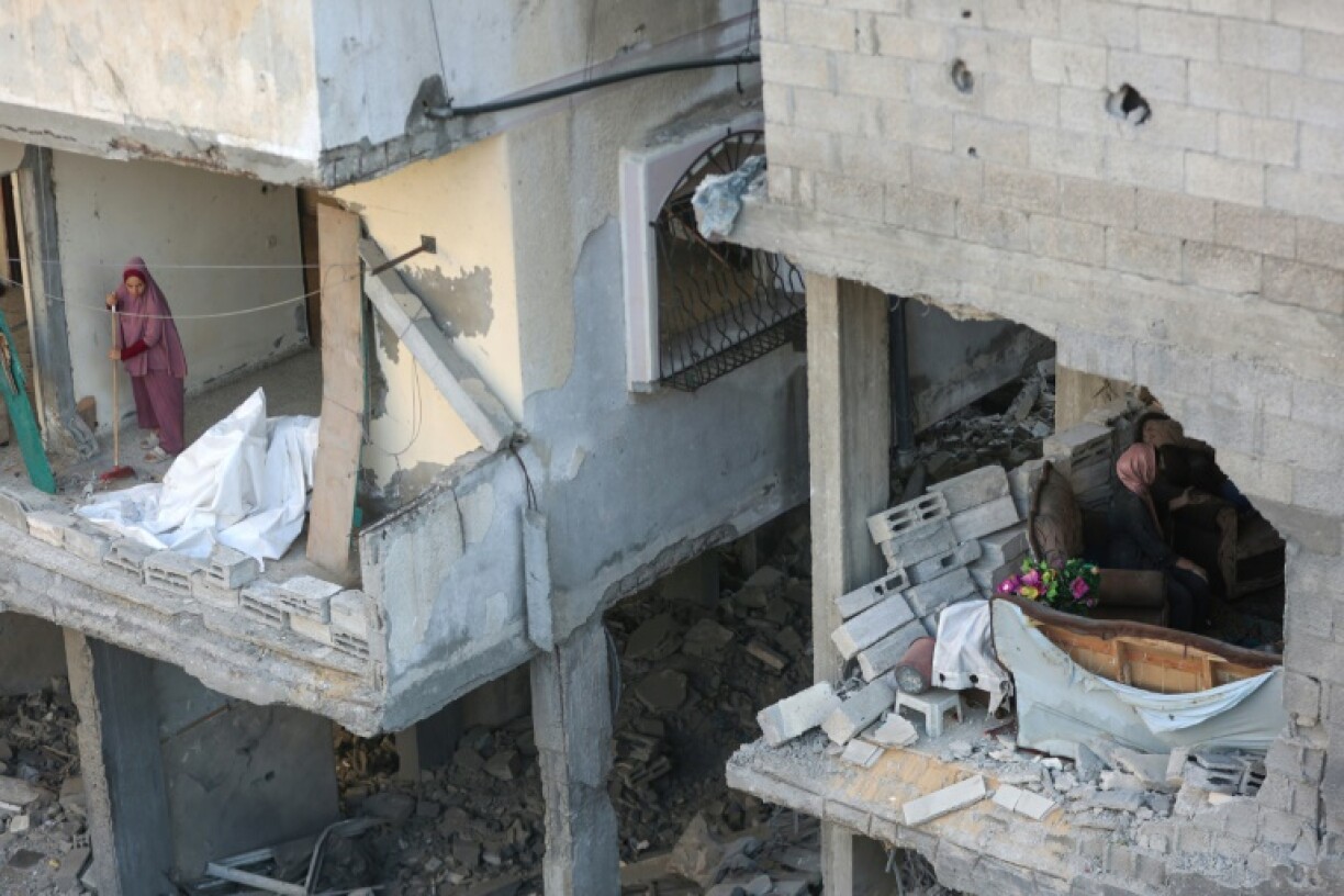 A Palestinian woman clears debris from her home after an Israeli strike on the Al-Shati refugee camp, west of Gaza City, on July 9, 2025