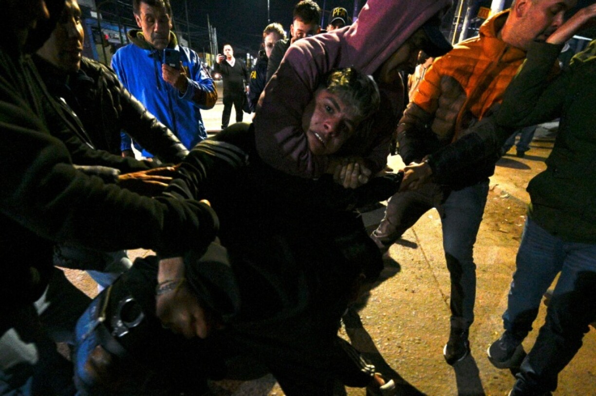 People restrain a man during a fight between supporters and opponents of Argentina's President Javier Milei at the end of a rally for the La Libertad Avanza political party