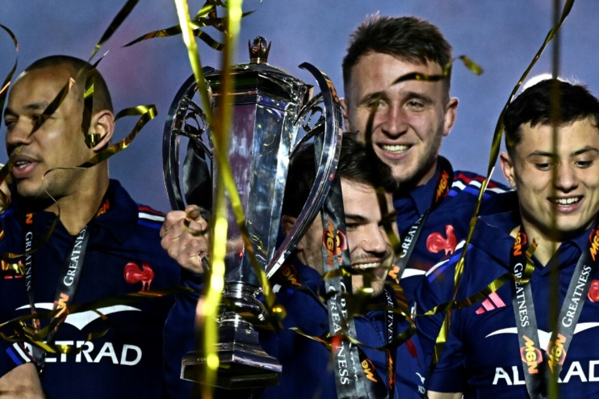 France's scrum-half Antoine Dupont (C) holds the trophy while celebrating winning the Six Nations