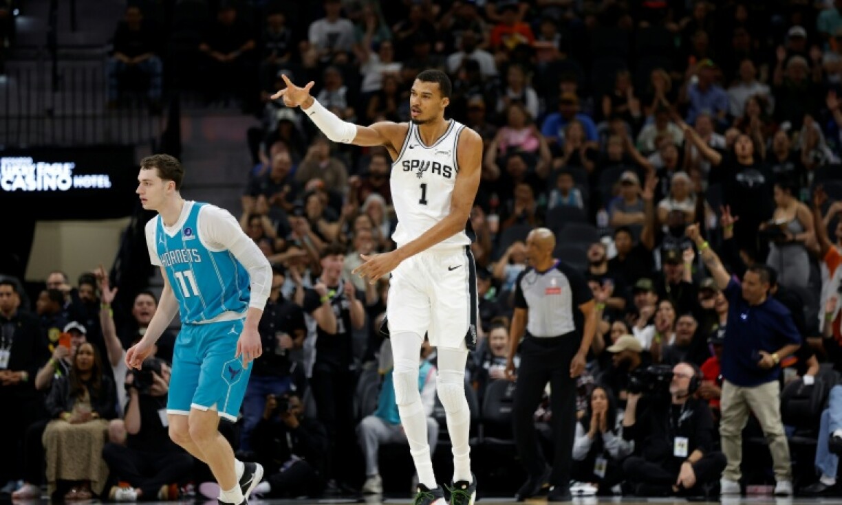 Victor Wembanyama (à droite), des San Antonio Spurs, réagit après un panier à trois points contre les Charlotte Hornets, le 14 mars 2026 à San Antonio, au Texas