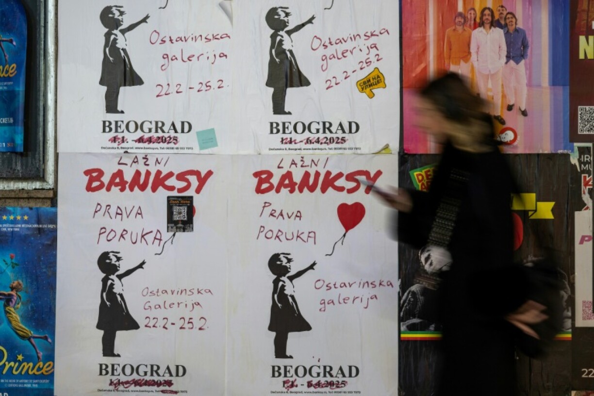 A woman walks past a poster advertising a Belgrade gallery where showcasing the work of secretive British artist Banksy